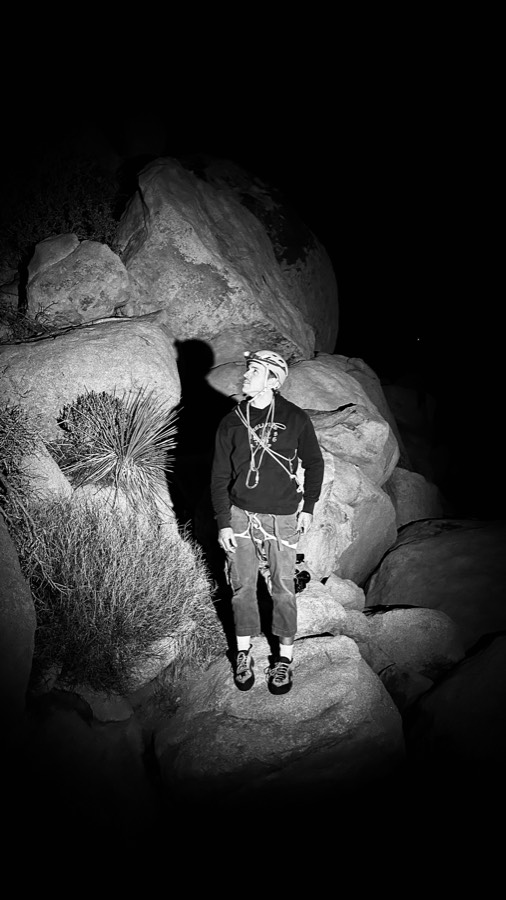 Andrea among granite boulders at night, lit by a single light.