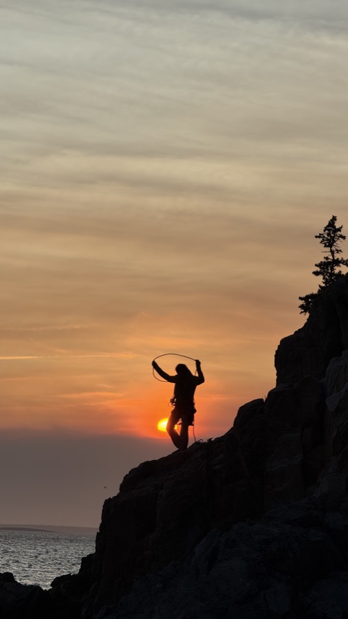 Andrea on a cliff edge over the ocean at sunset, Acadia.
