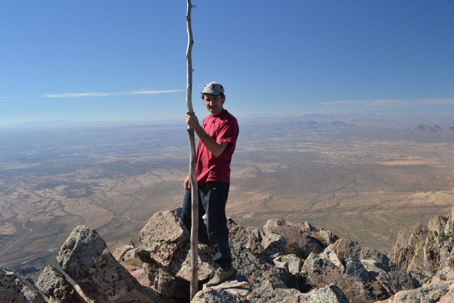 Andrea standing on a rocky summit with a walking stick.