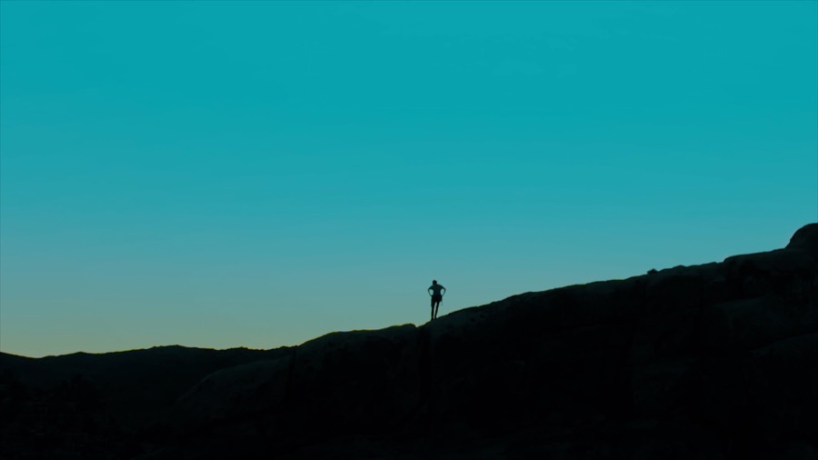 Andrea alone on a ridgeline at blue hour. Film still.