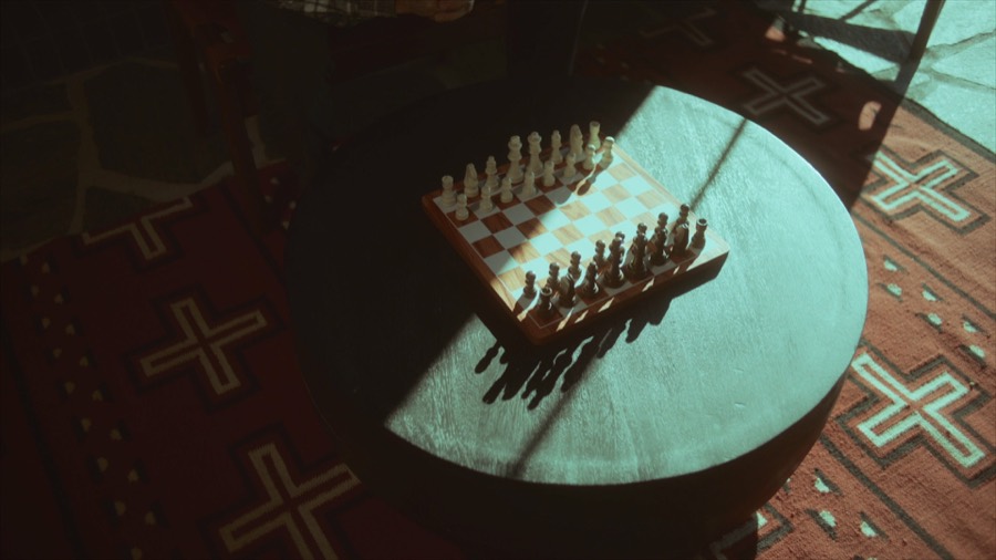 A chessboard in a pool of window light. Film still.